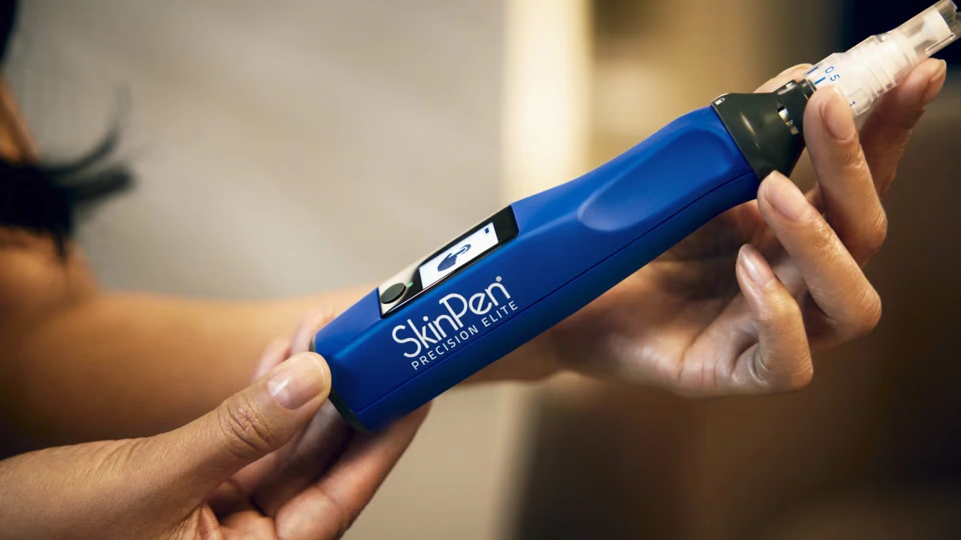 A person holds a blue SkinPen Precision Elite microneedling device, with the logo and a small screen visible on the handle—an advanced tool often featured at the Institute For Ageless Living to support wellness and anti-aging skincare routines.